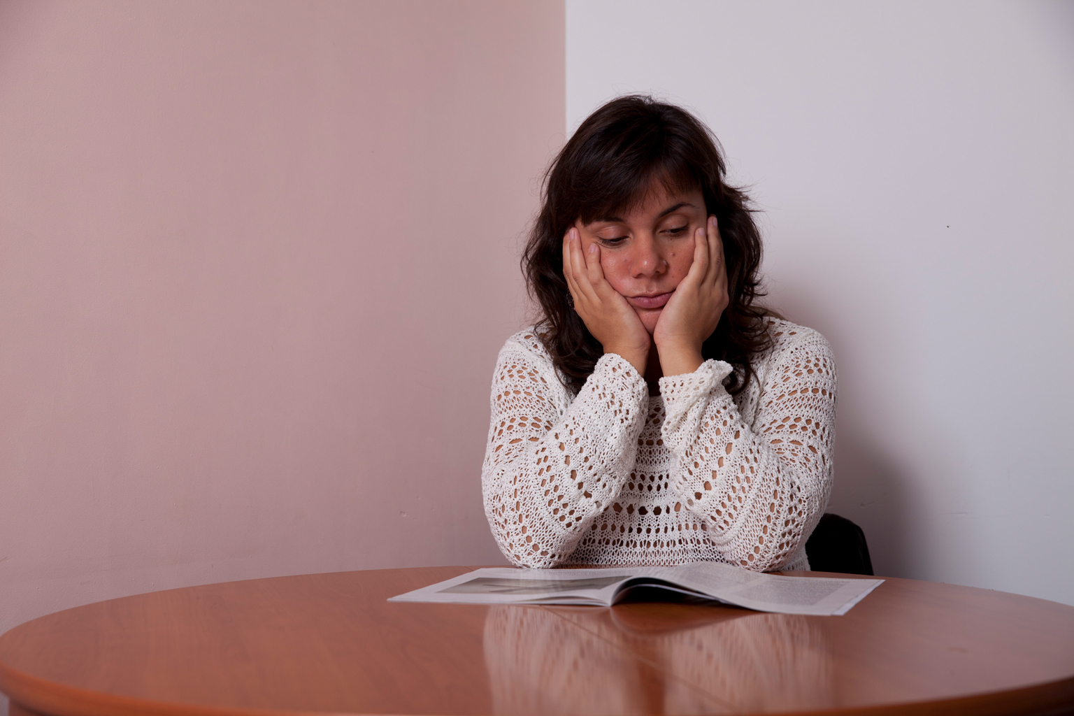 Frau lesend und sitzend am Tisch