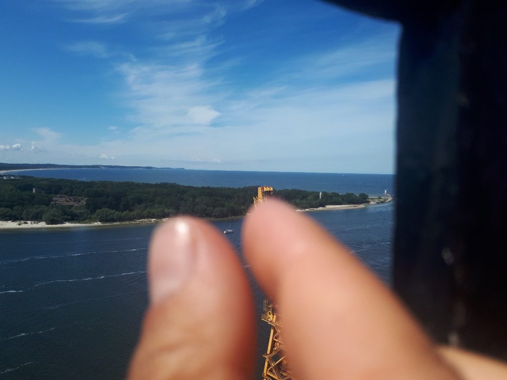 Zwei Finger rahmen weit entferntes Boot auf Meer ein